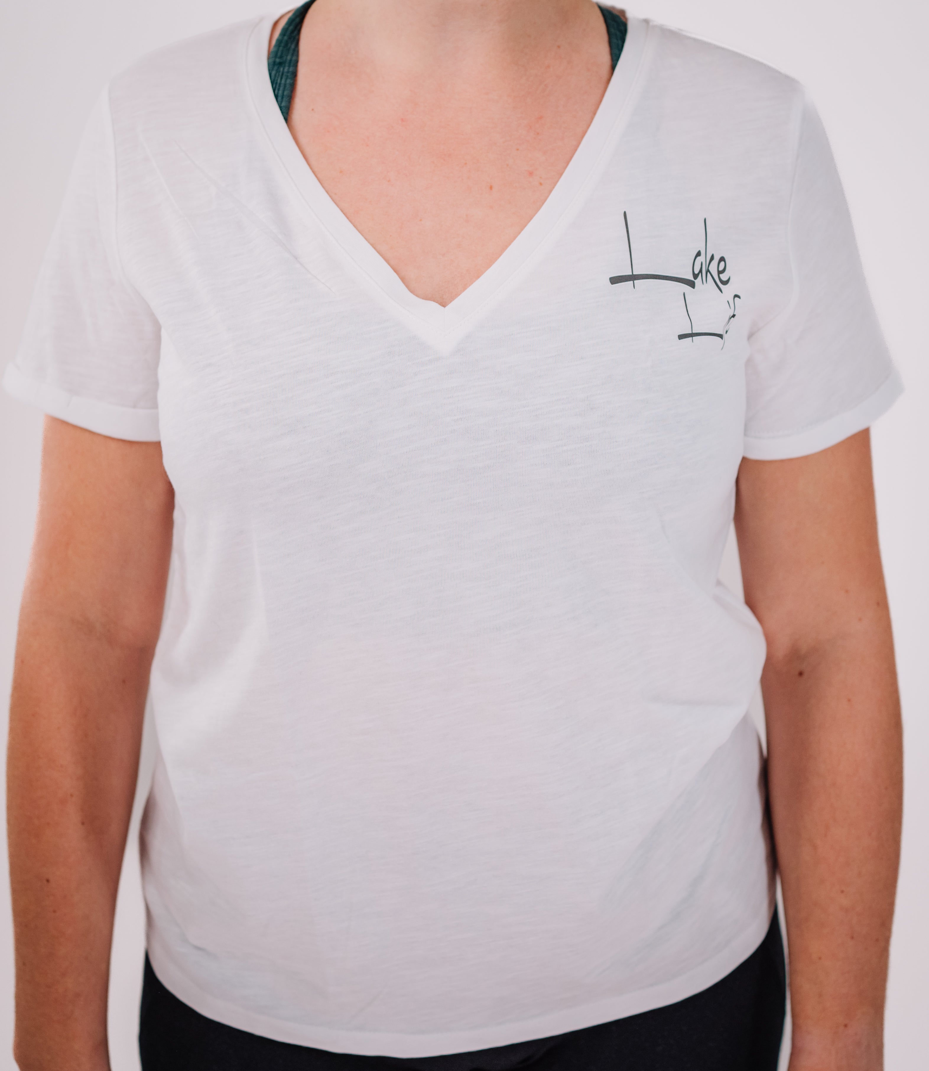 A woman wearing a white V-neck short-sleeve t-shirt with 'LAKE LIFE' text on the front.
