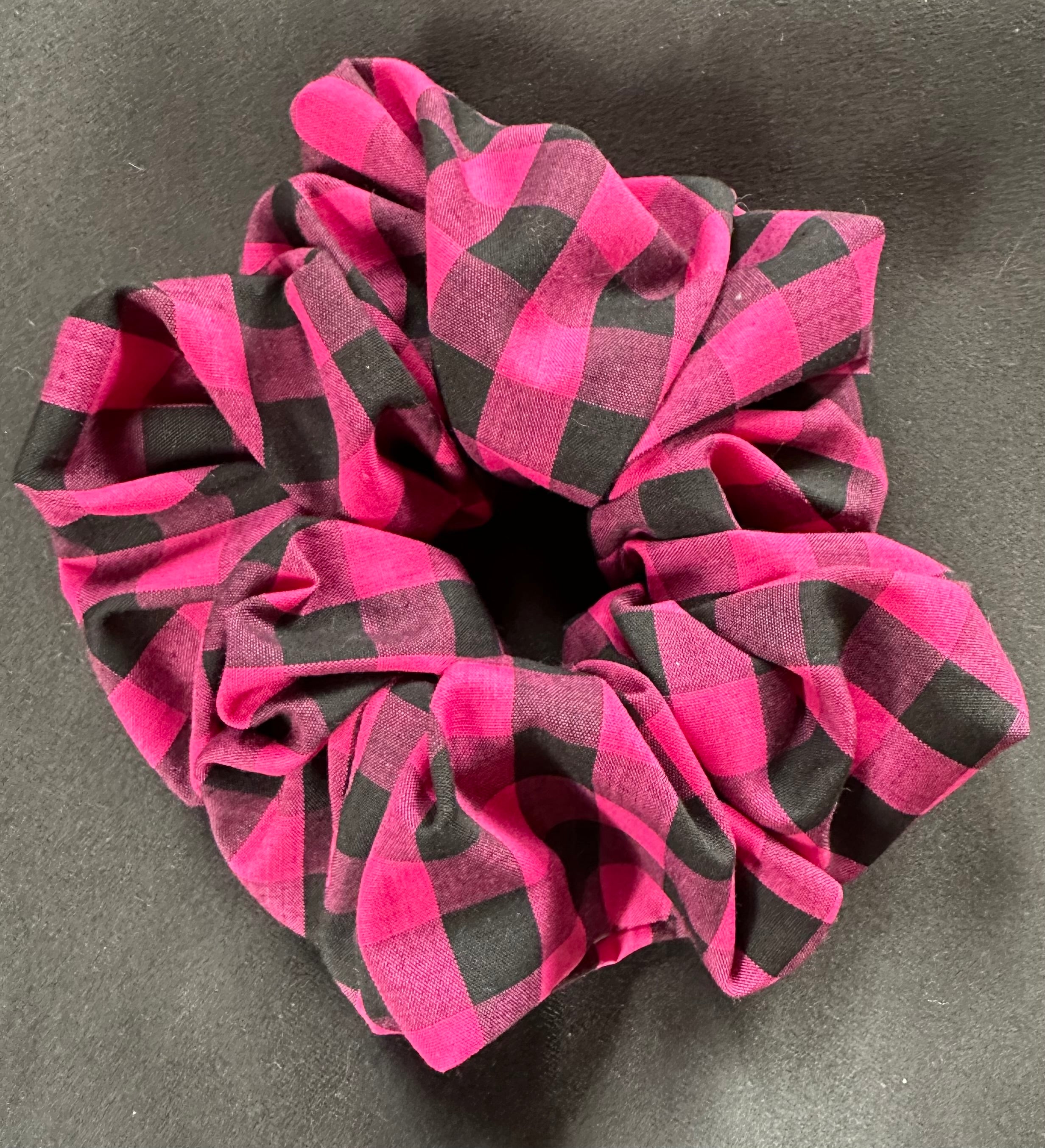 Pink and black checkered scrunchie on a gray background