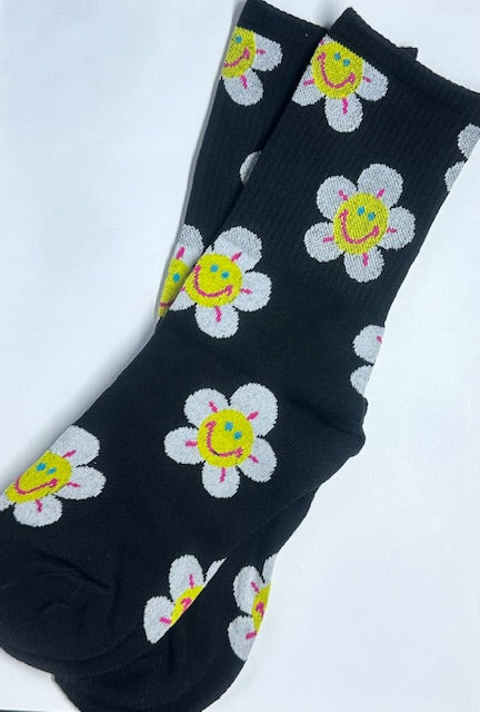 A pair of black ankle socks with colorful flower designs and smiley faces on them.